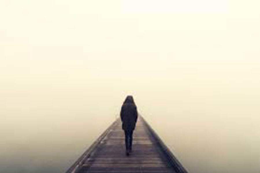 Person walking along foggy pier